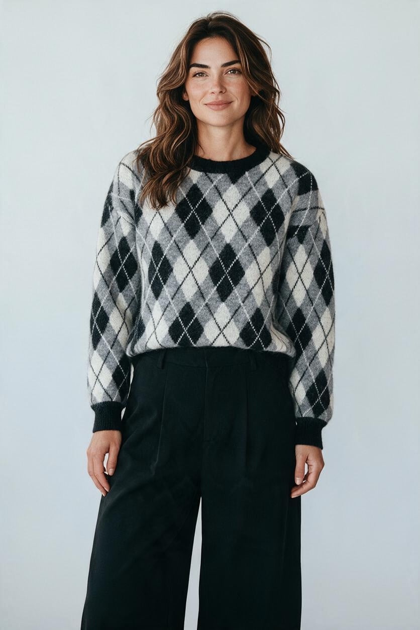 Plaza d'Amanté model wearing a black, grey, and white argyle knit crewneck sweater with ribbed trim and relaxed fit.