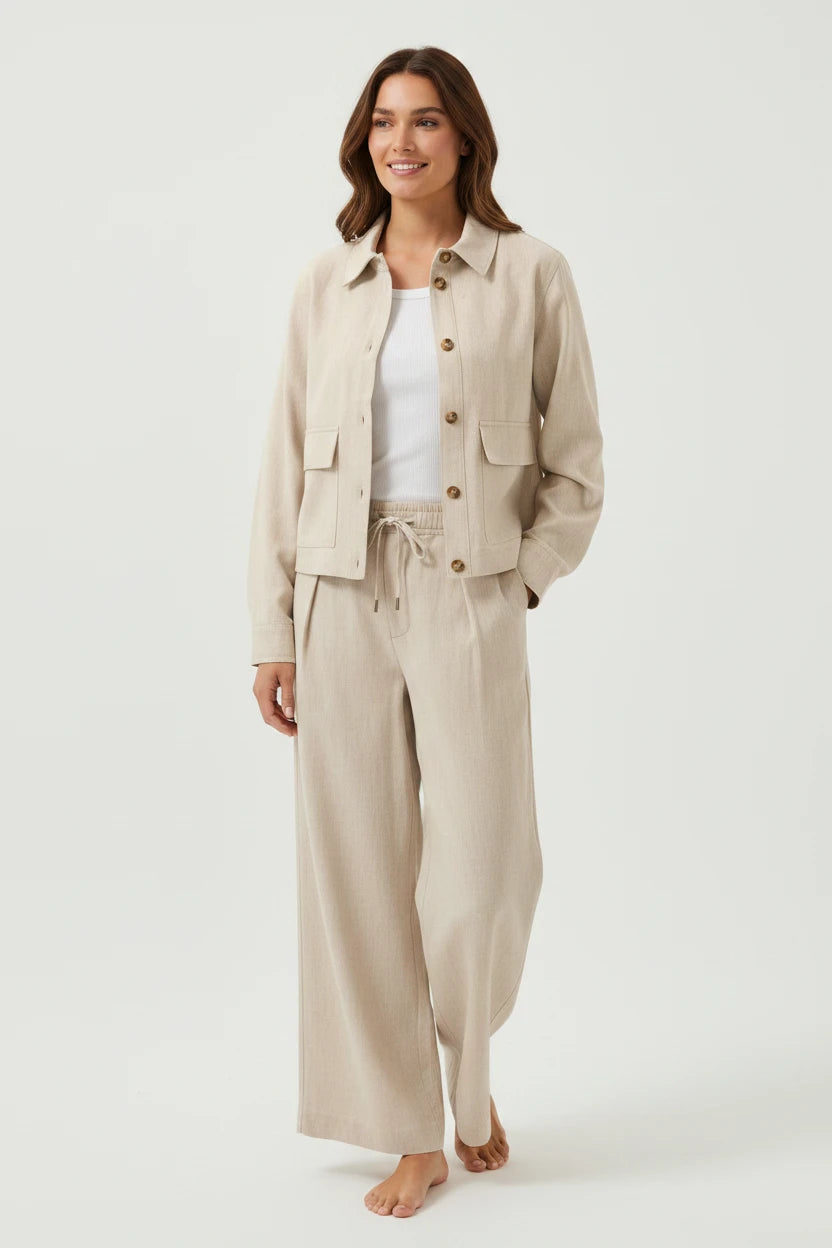 A model wearing a Plaza d'Amanté beige linen-blend button-down jacket and matching wide-leg drawstring trousers.