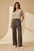 Plaza d'Amanté beige pointelle knit V-neck sweater paired with olive green high-waisted wide-leg tailored trousers.