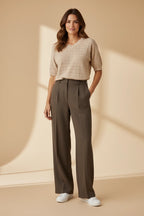 Plaza d'Amanté beige pointelle knit V-neck sweater paired with olive green high-waisted wide-leg tailored trousers.
