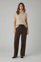 Plaza d'Amanté beige diamond-knit sleeveless turtleneck sweater vest paired with dark brown wide-leg trousers