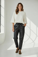 Plaza d'Amanté black faux leather joggers with elastic drawstring waist and knee seam details on a smiling model.