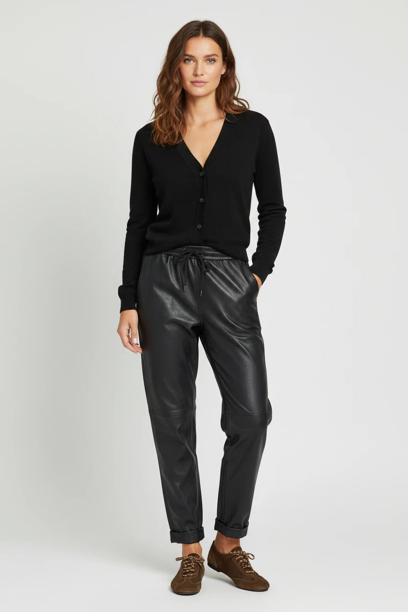 Plaza d'Amanté model wearing a black V-neck knit cardigan and black faux leather joggers with a drawstring waist.