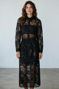 A model wearing a Plaza d'Amanté black floral lace midi shirt dress with long sleeves and sequin skirt details.