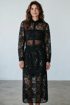 A model wearing a Plaza d'Amanté black floral lace midi shirt dress with long sleeves and sequin skirt details.