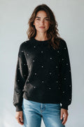 Plaza d'Amanté black knit sweater with scattered pearl embellishments, crew neck, and long sleeves on a model.