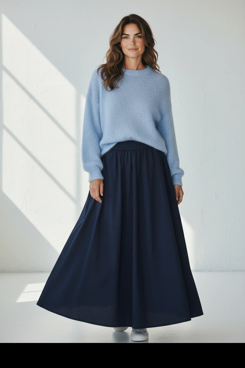 Plaza d'Amanté model wearing a fuzzy powder-blue knit sweater and a flowing navy blue A-line maxi skirt.