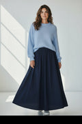 Plaza d'Amanté model wearing a fuzzy powder-blue knit sweater and a flowing navy blue A-line maxi skirt.