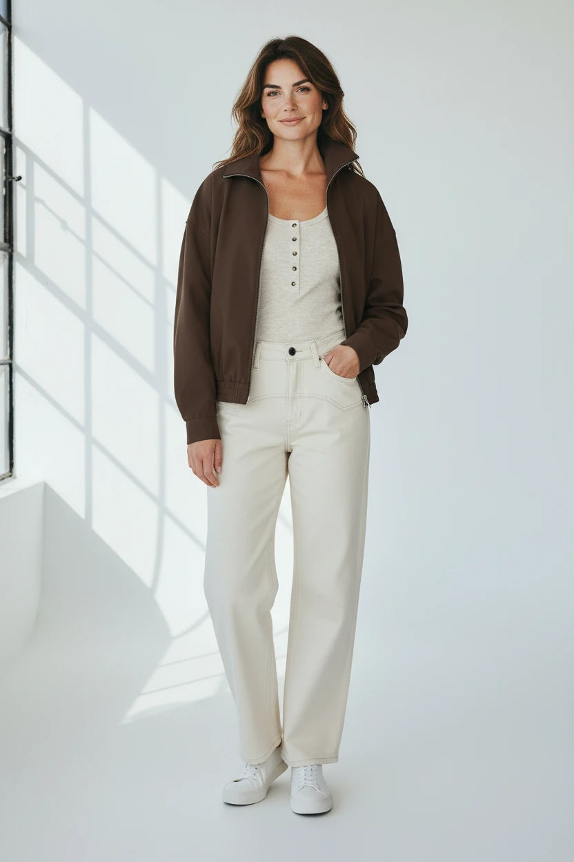 Plaza d'Amanté chocolate brown zip-up bomber jacket worn with high-rise cream denim pants and a henley top