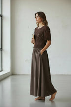 Plaza d'Amanté brown crochet knit top and matching maxi skirt set with scalloped edges and side pockets on a model.