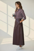 Plaza d'Amanté espresso brown faux leather midi skirt with side pockets, styled with a striped shirt and sneakers.