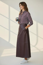 Plaza d'Amanté espresso brown faux leather midi skirt with side pockets, styled with a striped shirt and sneakers.