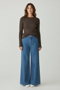 Plaza d'Amanté espresso brown ribbed long-sleeve knit sweater with lettuce-edge trim worn with wide-leg blue jeans.
