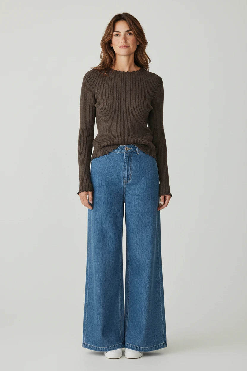 Plaza d'Amanté espresso brown ribbed long-sleeve knit sweater with lettuce-edge trim worn with wide-leg blue jeans.