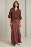 Plaza d'Amanté model wearing a chocolate brown knit polo sweater and a matching mocha satin maxi skirt with sneakers.