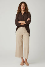 Plaza d'Amanté model wearing a chocolate brown button-down shirt and beige high-rise wide-leg cropped utility pants.