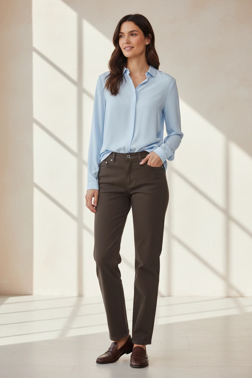 Plaza d'Amanté women wearing a light blue button-down shirt and brown straight-leg trousers with brown loafers.