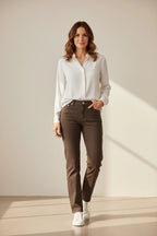 Plaza d'Amanté model wearing a white button-down shirt and straight-leg brown trousers with white sneakers