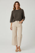 Plaza d'Amanté espresso brown knit sweater with cream trim worn with beige cropped wide-leg denim pants by a model.