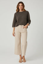 Plaza d'Amanté espresso brown knit sweater with cream trim worn with beige cropped wide-leg denim pants by a model.