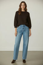 Plaza d'Amanté model wearing a dark brown textured knit sweater and light-wash high-rise straight-leg patch pocket jeans