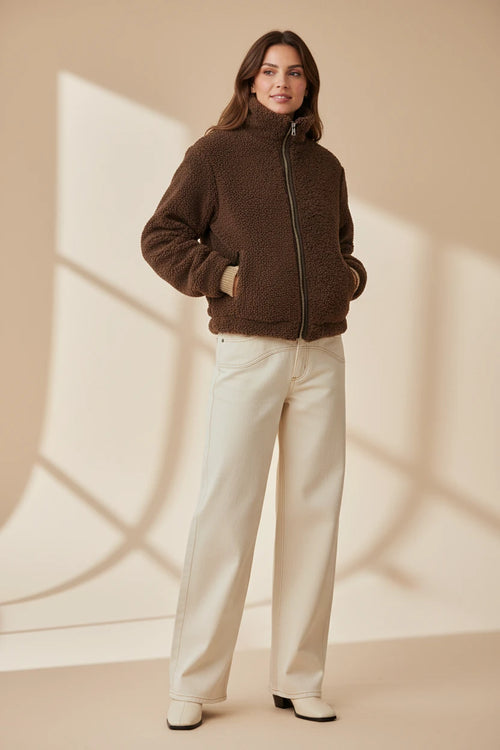 Plaza d'Amanté chocolate brown teddy fleece zip-up jacket with a mock-neck collar worn by a model in cream jeans.