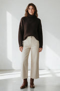Plaza d'Amanté model wearing a dark brown textured turtleneck sweater and cream high-waisted wide-leg cotton trousers.
