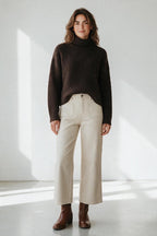 Plaza d'Amanté model wearing a dark brown textured turtleneck sweater and cream high-waisted wide-leg cotton trousers.