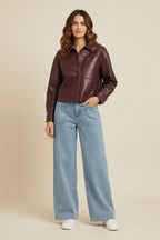 Model wearing a Plaza d'Amanté deep burgundy faux leather shirt jacket with patch pockets and light wash wide-leg jeans