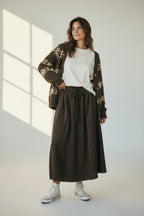 Plaza d'Amanté chocolate brown high-waisted maxi skirt with a drawstring waist and side pockets on a smiling model.
