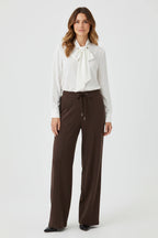 Plaza d'Amanté high-waisted wide-leg trousers in chocolate brown with a drawstring waist and front seam detail.