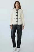 Plaza d'Amanté cream boucle jacket with black contrast piping, collarless design, and button front on a female model.