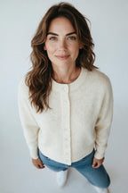 A woman wearing a Plaza d'Amanté cream-colored knit cardigan with a crew neck and button-front closure.