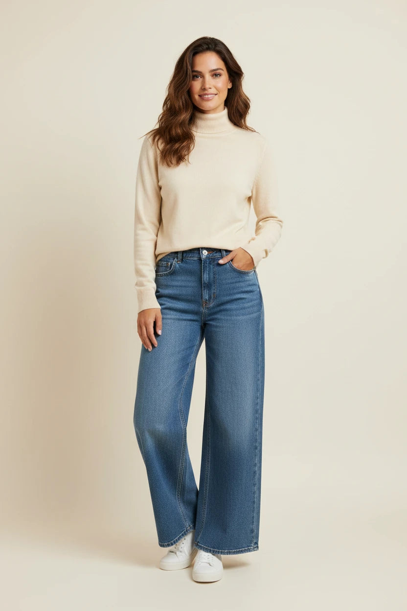 Plaza d'Amanté model wearing a cream turtleneck sweater and high-waisted wide-leg blue denim jeans with white sneakers
