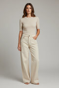 Plaza d'Amanté model wearing a beige fine-knit short-sleeve sweater and cream high-waisted wide-leg denim trousers.
