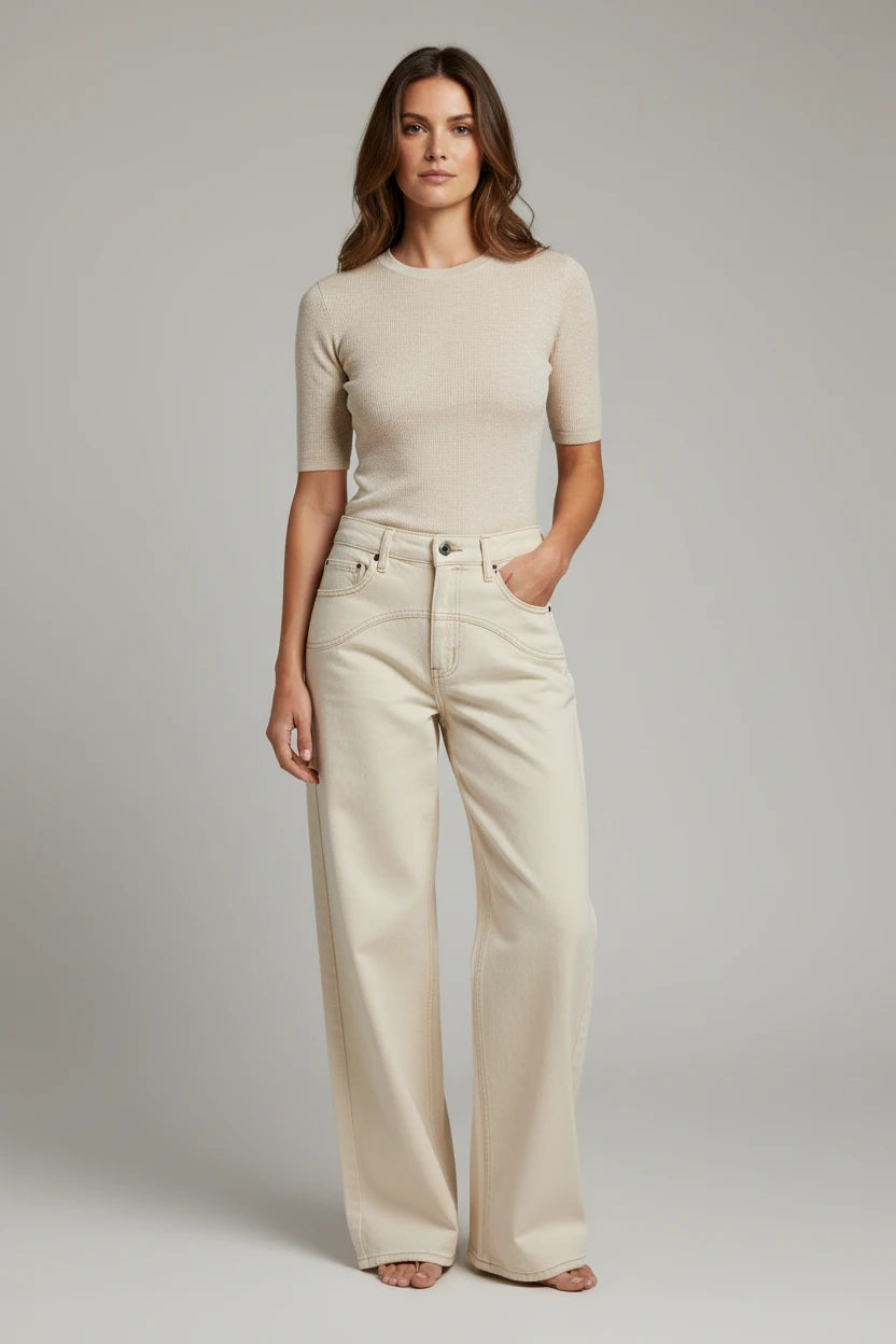 Plaza d'Amanté model wearing a beige fine-knit short-sleeve sweater and cream high-waisted wide-leg denim trousers.