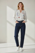 Plaza d'Amanté long sleeve pinstripe blouse with colorful seahorse and bird embroidery worn with dark denim jeans.