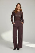 A smiling model wearing Plaza d'Amanté espresso brown wide-leg tailored trousers with a high-rise waist and pockets.