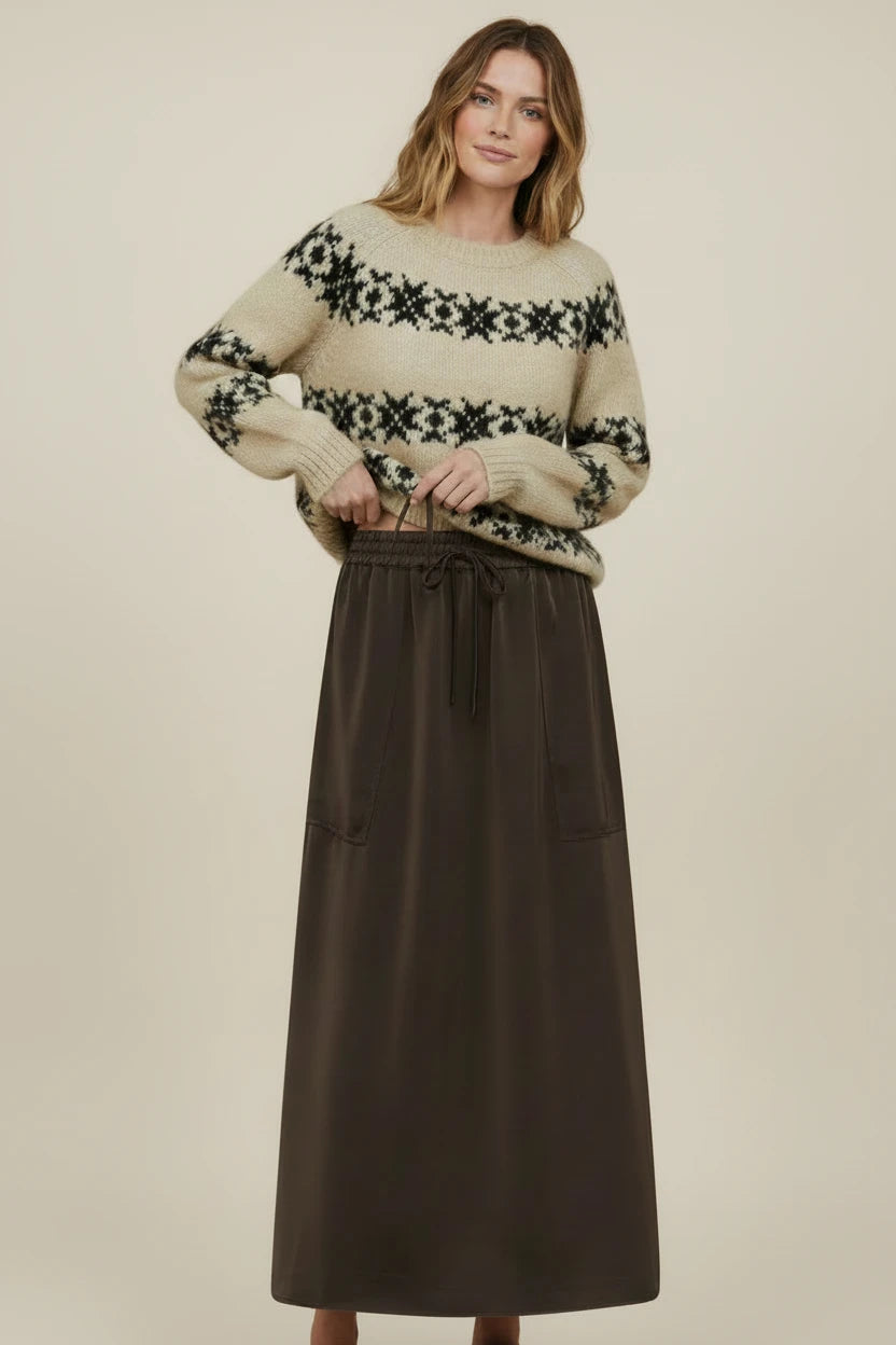 Plaza d'Amanté model wearing a cream and black Fair Isle knit sweater with a dark brown midi skirt and side pockets.