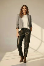 Plaza d'Amanté model wearing a grey tailored blazer, white t-shirt, and black faux leather joggers with ankle boots.