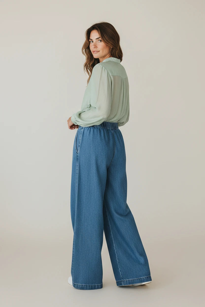 Plaza d'Amanté high-waisted wide-leg denim trousers in medium blue with an elastic waistband worn by a woman