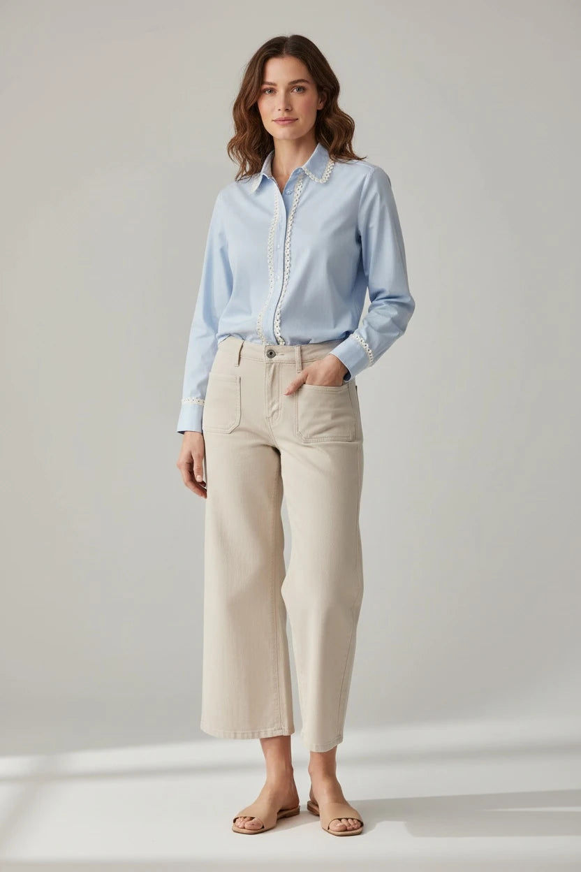 Plaza d'Amanté light blue cotton button-down shirt with white lace trim on placket and cuffs worn with beige trousers.