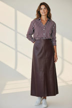 Model wearing a Plaza d'Amanté mahogany faux leather A-line maxi skirt with a striped button-down shirt and sneakers.