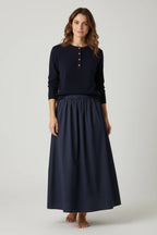 Model wearing a Plaza d'Amanté navy blue long-sleeve henley sweater and a matching flowing cotton maxi skirt.