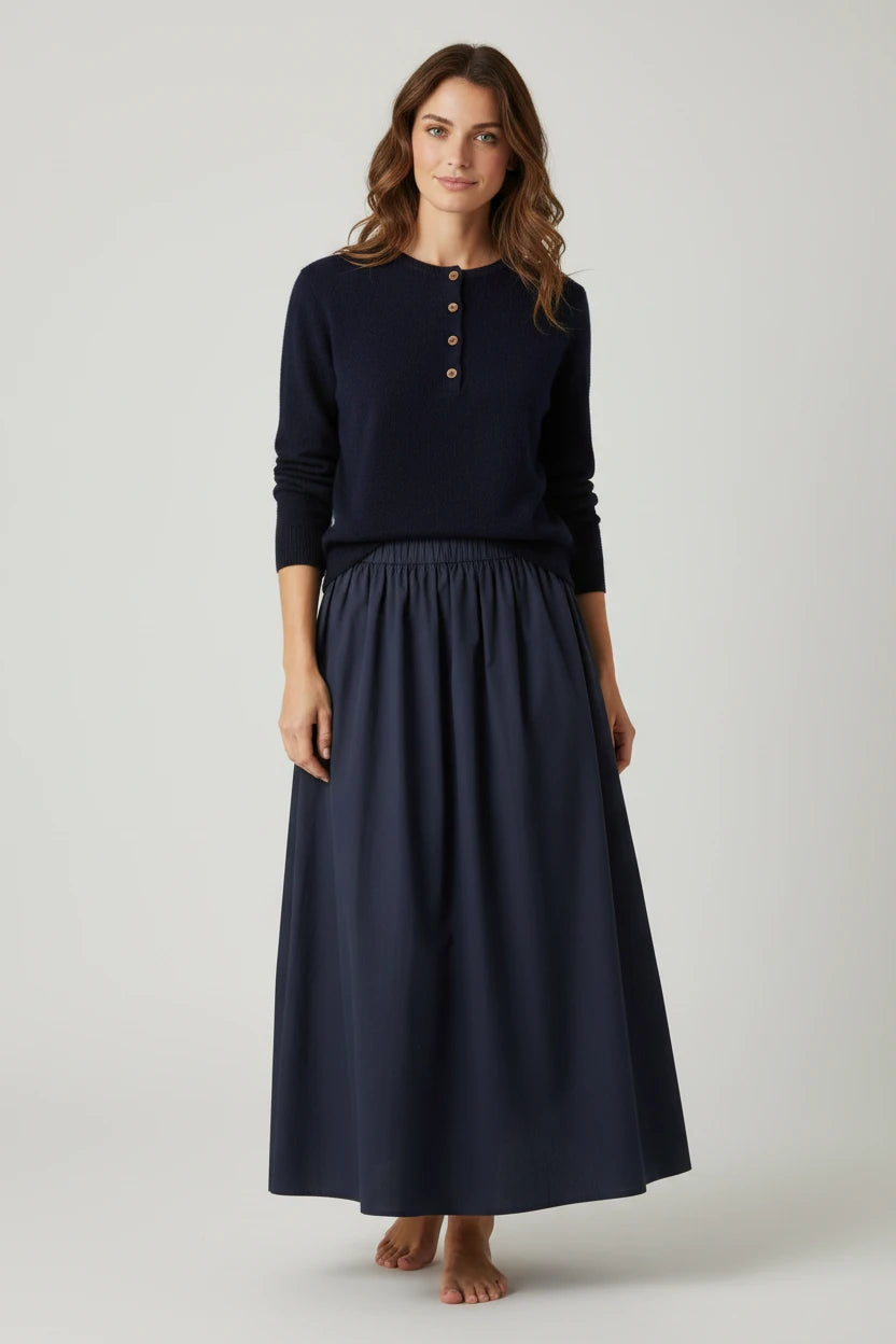 Model wearing a Plaza d'Amanté navy blue long-sleeve henley sweater and a matching flowing cotton maxi skirt.
