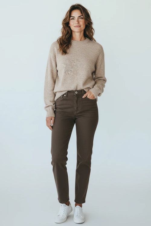 Plaza d'Amanté oatmeal crewneck sweater and chocolate brown straight-leg denim jeans worn by a woman with sneakers.