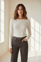 Plaza d'Amanté off-white long sleeve crew neck knit top worn by a woman with dark jeans in a sunlit room.