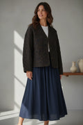 Plaza d'Amanté olive brown diamond-quilted button-front jacket with a V-neck collarless design worn by a woman.