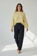 Model wearing a Plaza d'Amanté pale yellow fuzzy knit sweater with a crew neck and dark denim jeans