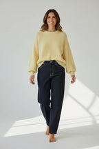 Model wearing a Plaza d'Amanté pale yellow fuzzy knit sweater with a crew neck and dark denim jeans